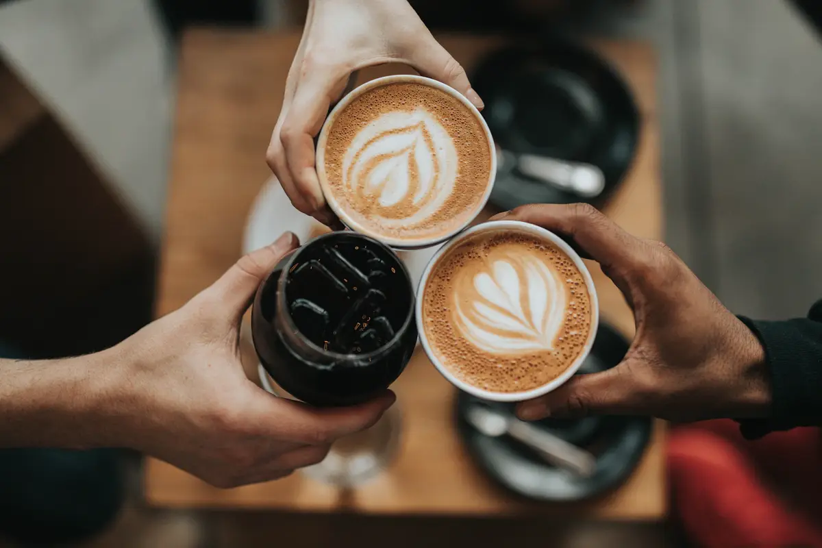 Three cups of coffee held over a café table