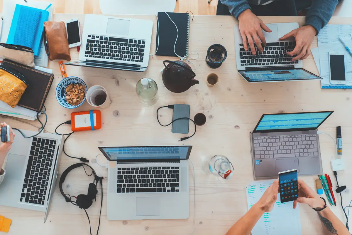 Phones, laptops and notebooks spread across a wooden table